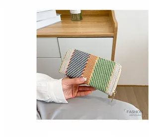 Close-up of a colorful woven linen long wallet held by hand in a modern interior setting