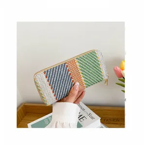 Close-up view of a colorful woven linen long purse being held over a wooden tray.