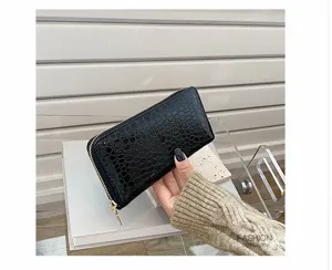 Vista detallada de una cartera negra para mujer con patrón de cocodrilo y cremallera dorada
