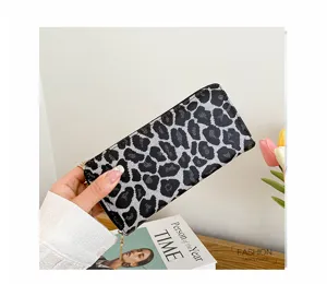Detailed close-up of a stylish leopard print clutch wallet held by hand with flowers