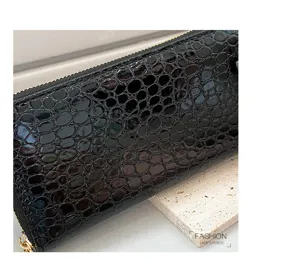 Detalle macro de una cartera de mujer negra con patrón de cocodrilo y acabado brillante.