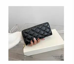 Close-up detail of a stylish black quilted long wallet for women held by hand