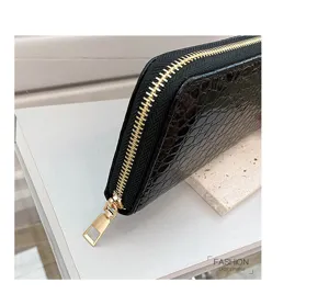Detalle de cartera negra con relieve de cocodrilo y cremallera dorada de diseño moderno.