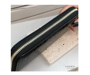 Primer plano del cierre dorado en una cartera de mujer con relieve de cocodrilo negro