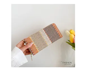 Detailed macro view of an orange and beige woven plaid ladies purse held in hand