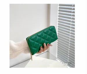 Detail view of a green quilted long wallet featuring glossy finish and gold zipper.
