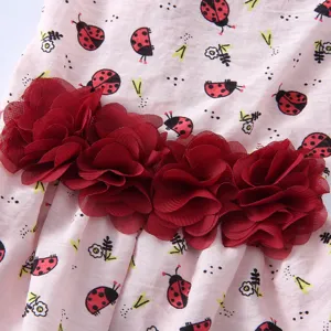 Gros plan détaillé d'une jolie robe d'été pour animal avec imprimé coccinelle et fleurs.