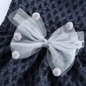 Gros plan détail de robe pour animal avec nœud en tulle gris et pompons duveteux.