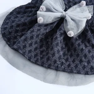 Vue détaillée d'une robe de chien élégante avec nœud en tulle et pompons pour fête de mariage.
