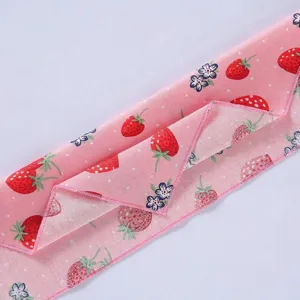 Gedetailleerde weergave van de aardbeienprint en fijne randstiksels op de roze huisdier bandana