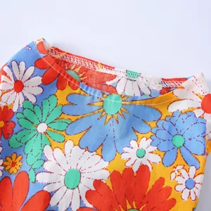 Gros plan détaillé montrant le motif floral vibrant et les coutures soignées de la robe d'été.