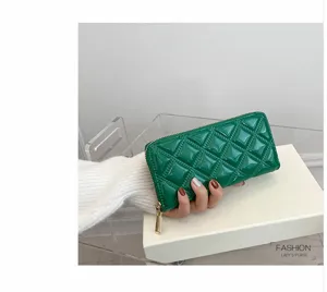 Close-up detail of a stylish green quilted long zipper wallet for women on a gift box