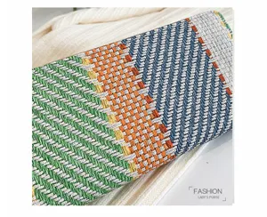 Close-up detail of a colorful geometric woven linen clutch bag with intricate texture