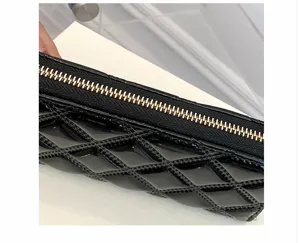 Close-up view of golden zipper and black quilted patent leather on long purse detail