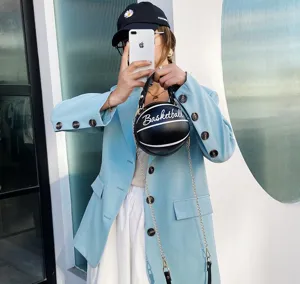 Modelo con chaqueta azul sosteniendo un bolso creativo con forma de baloncesto
