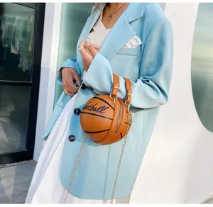 Detalle de un bolso moderno con forma de baloncesto, cadena dorada y asas de cuero