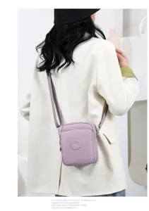 Vista detallada de un pequeño bolso bandolera de tela Oxford morada usado por una modelo