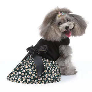 Détail de robe pour animal avec motif marguerites, nœud noir et tissu confortable.