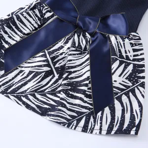 Détail de robe pour animal avec haut côtelé bleu, jupe à motif de feuilles et beau nœud.