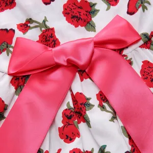 Close-up detail of a floral print pet dress featuring a vibrant pink satin bow embellishment