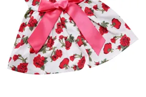 Detail close-up of a floral pet dress featuring a pink satin bow and red rose pattern