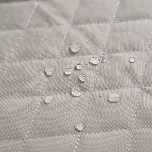 Waterproof quilted pet car seat cover fabric detail showing water repellent droplets close up.