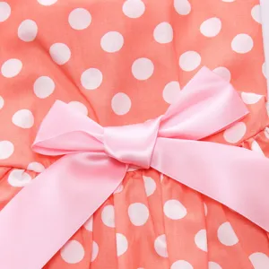 Detailed view of a pink satin bow ornament on an orange polka dot pet summer dress fabric