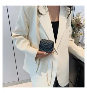 Primer plano de un bolso bandolera vintage con monograma y cadena dorada fina