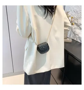 Primer plano de un mini bolso bandolera vintage a cuadros negros con cadena dorada