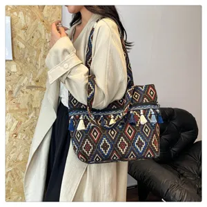 Bolso tote de estilo étnico con estampados geométricos y borlas, llevado por una modelo.