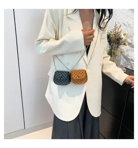 Minibolsos bandolera con estampado de monograma llevados por modelo en blazer.