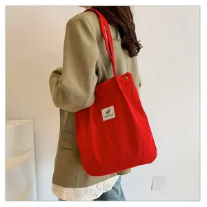 Detalle de un bolso de pana roja vibrante llevado sobre una chaqueta blazer de color caqui.