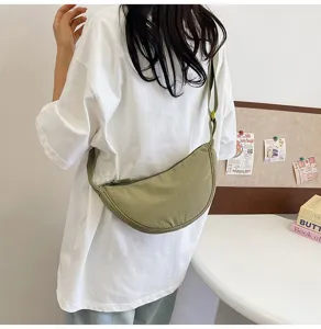 Bolso dumpling de nailon verde llevado como bandolera por una modelo, vista trasera