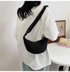 Elegante bolso bandolera de nailon negro en forma de media luna visto desde atrás