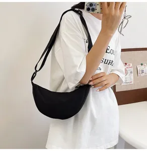 Vista detallada de un bolso bandolera de nailon negro llevado por una modelo en selfie