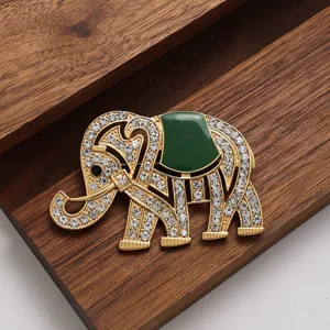 Gros plan détaillé d'une broche éléphant dorée étincelante avec émail vert sur bois