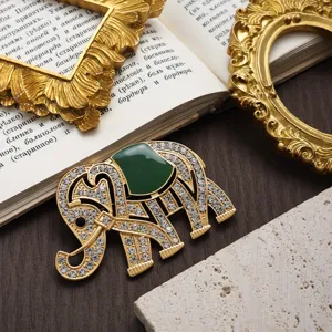 Détail d'une luxueuse broche éléphant dorée avec strass étincelants et émail vert