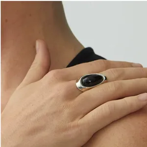 Dettaglio di un anello minimalista in argento con una grande pietra di ossidiana ovale.