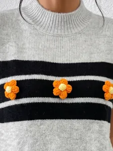 Gros-plan d'un gilet en tricot pour femme avec motif rayé et fleurs crochetées à la main.