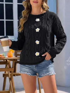 Vista detallada de un jersey negro de punto trenzado con aplicaciones florales 3D y mangas largas.