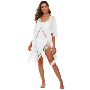 Detail view of white crochet hollow out beach cover up with tassels and flare sleeves.