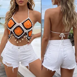 Handcrafted crochet halter crop top with shell pendants paired with white denim shorts for beach.