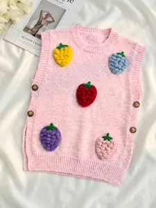 Detalle de un chaleco de punto rosa con aplicaciones de fresas de ganchillo en 3D.