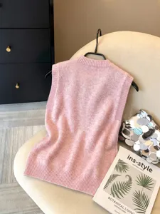 Primer plano de un chaleco de punto rosa para mujer sobre una silla beige