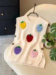 Detalle de un chaleco de punto crema con aplicaciones de fresas coloradas en 3D