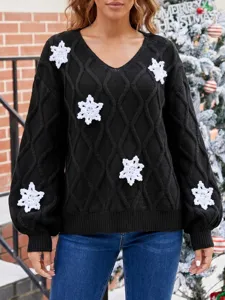 Detailaufnahme des schwarzen V-Ausschnitt Strickpullovers mit Häkel-Schneeflocken Mustern.