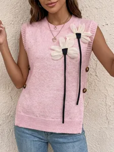 Close-up of pink knit vest featuring 3D floral appliques and side button decorations