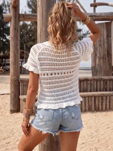 Close-up of white crochet knit beach cover-up with intricate hollow-out texture.