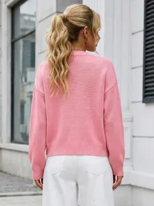 Vista posteriore di un morbido cardigan rosa in maglia abbinato a pantaloni bianchi chic.