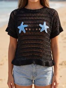 Detailed view of a black crochet knit cover-up top featuring blue starfish appliques on beach.